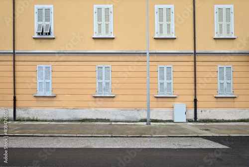 Facade of a residential building from the early twentieth century with closed shutters. Concrete sidewalk and paved road in front. Background for copy space © luca piccini basile