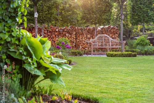 Zielony trawnik z drewnianą ławką w ogrodzie w angielskim stylu