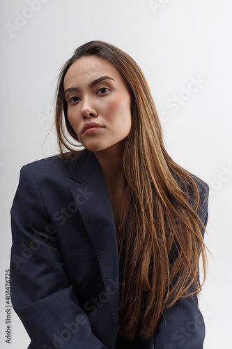 portrait of young attractive asian woman with long hair in blue suit isolated on white background. skinny stylish pretty female posing at studio. model tests of beautiful lady © Artem Zatsepilin