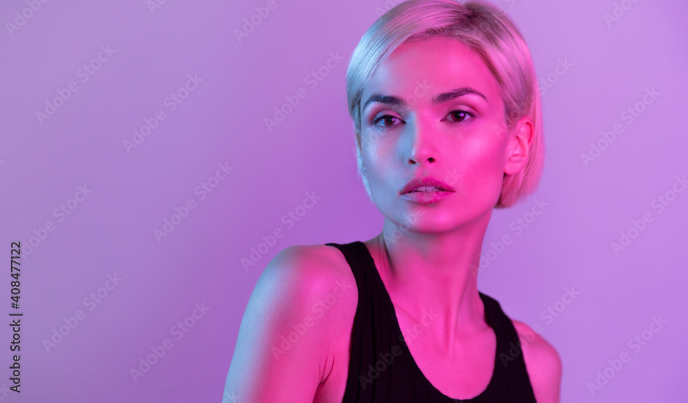 Blond young female with perfect skin in black dress in neon light Blond young female with perfect skin in black dress in neon light