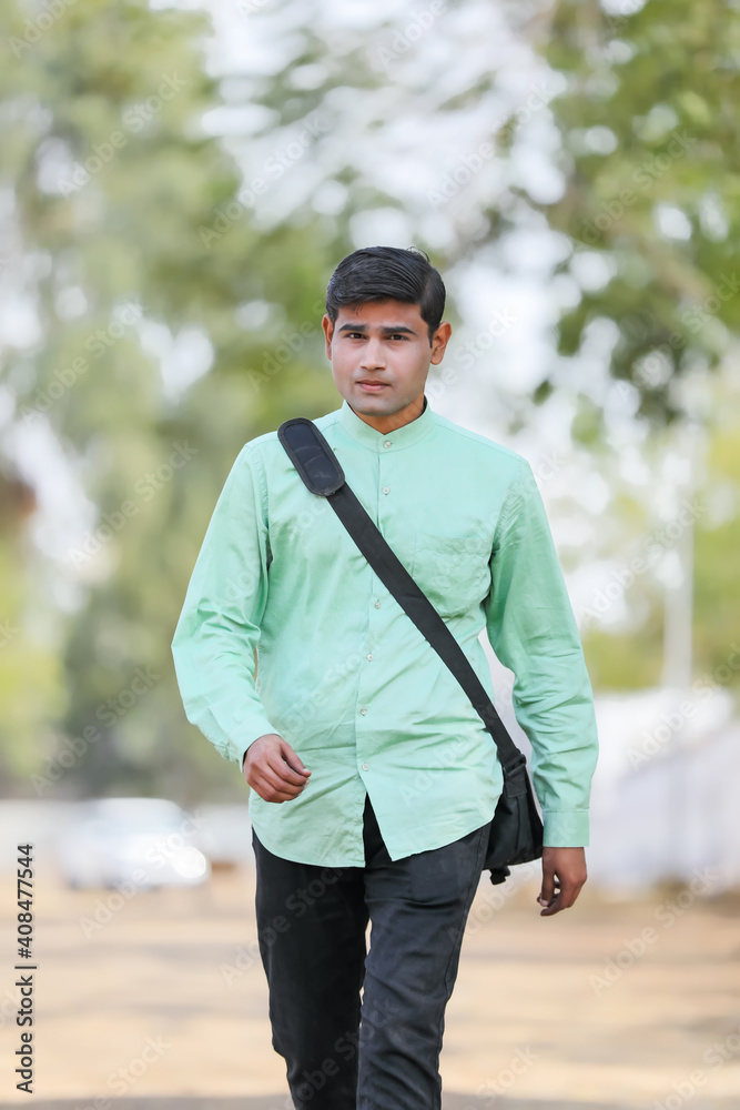 Young Indian male model standing and holding the office bag and giving expression. Young Indian male model standing and holding the office bag and giving expression.