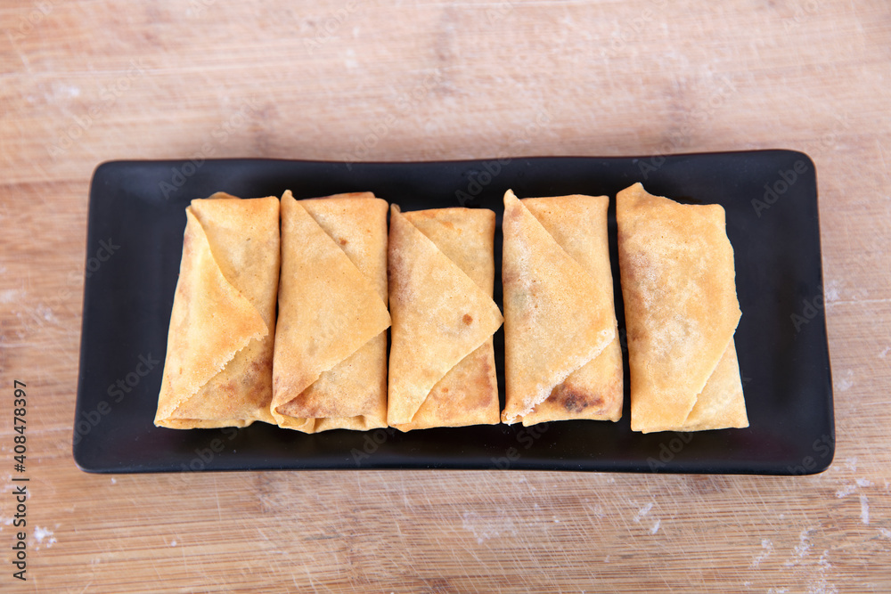 Overlooking a plate of fried spring rolls on the cutting board Overlooking a plate of fried spring rolls on the cutting board
