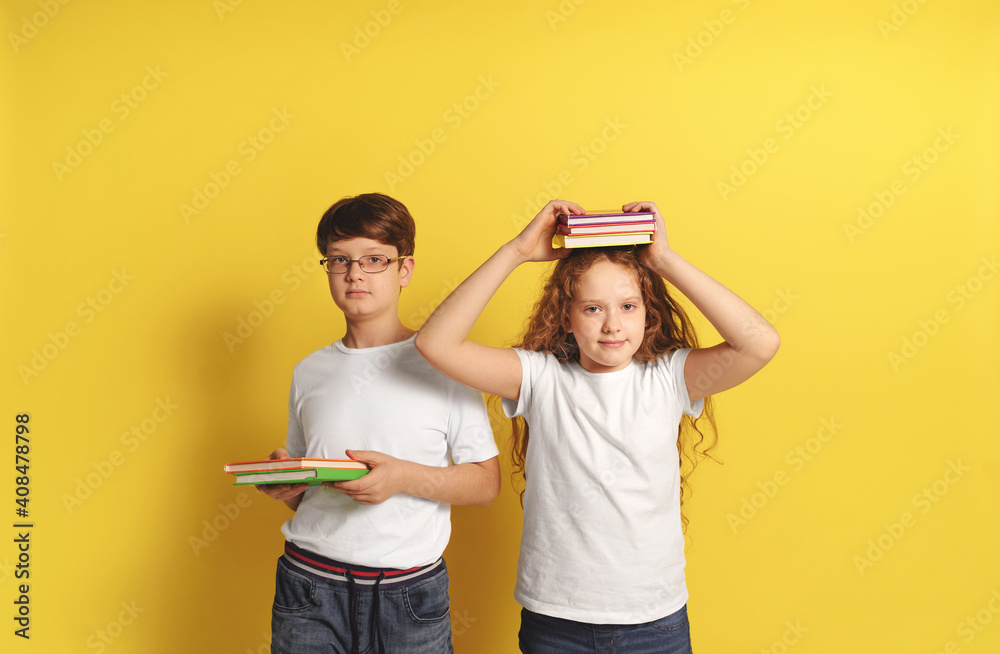 Children with books in the studio on a yellow background.