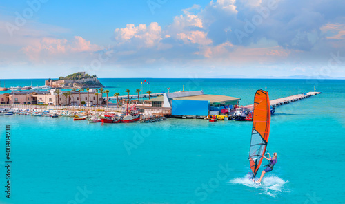 Beautiful cloudy sky with Windsurfer Surfing The Wind On Waves - Pigeon Island with a "Pirate castle". Kusadasi harbor, Aegean coast of Turkey.