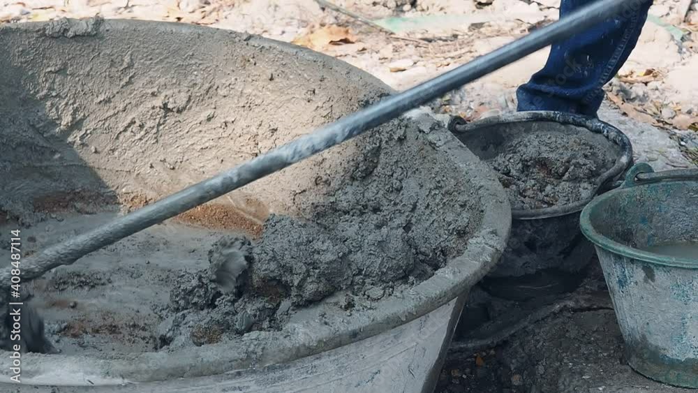 Construction worker mixes wet grey cement in basin. Construction worker mixes wet grey cement in basin.