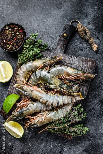 Raw black tiger prawns, shrimps and spices. Black background. Top view