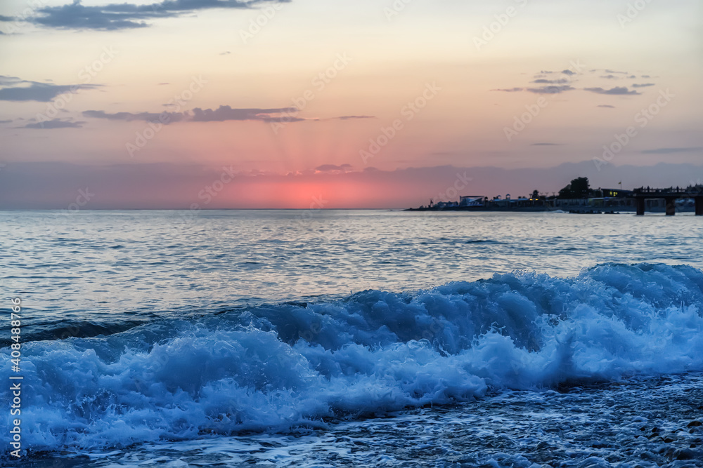 Sunset over the sea in pink colors and waves at the shore. Vacation at sea 
