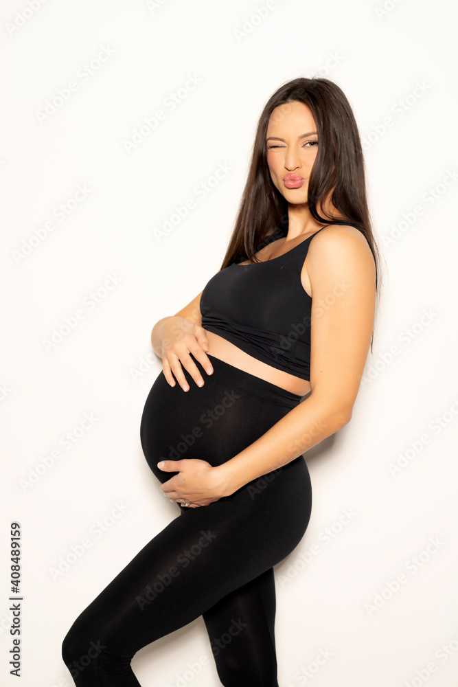 a pregnant young woman posing in black leggings and a shirt a pregnant young woman posing in black leggings and a shirt