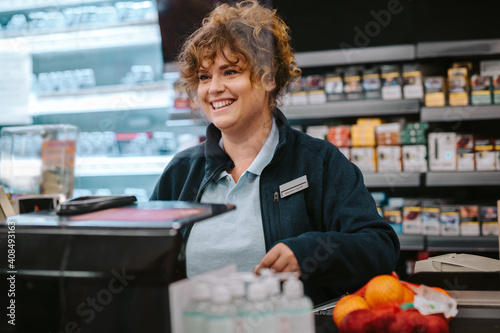 Happy cashier at supermarket checkout photo