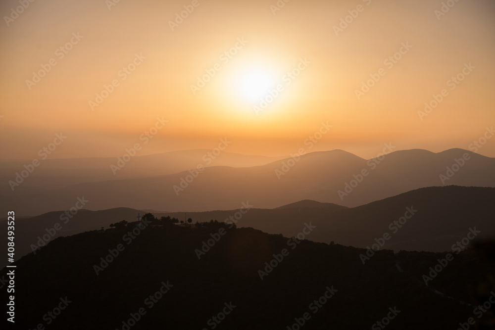 Panorama of a hilly landscape with several levels: romantic sunset in Greece in warm colors
