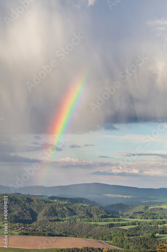 Cloudy sky with a rainbow in bright colors in the nature reserve of Saxon Switzerland