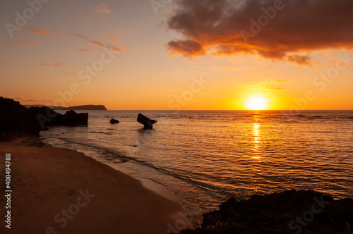 Vibrant warm sunset with orange and yellow colors, and some rocks typical from Okinawa seashore. Iriomote Island.