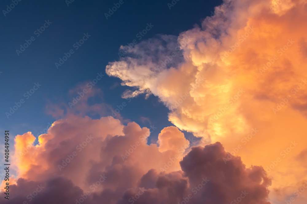 Yellow, orange and pink clouds formation illuminated by a magic sunlight decorate the blue sky. Cumulonimbus.