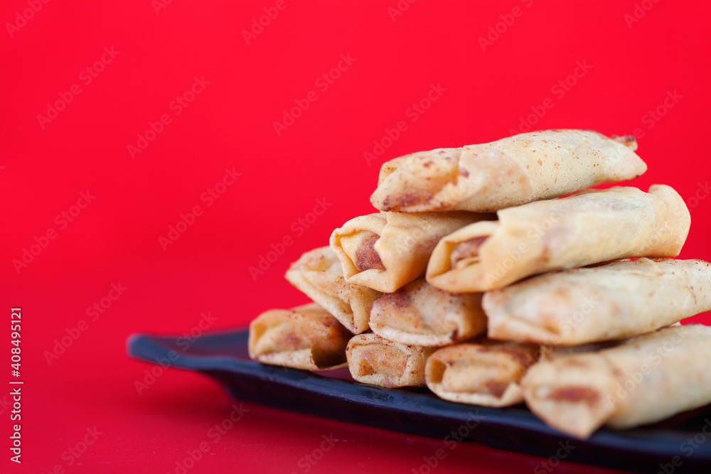 A plate of fried spring rolls at the beginning of spring on a red background