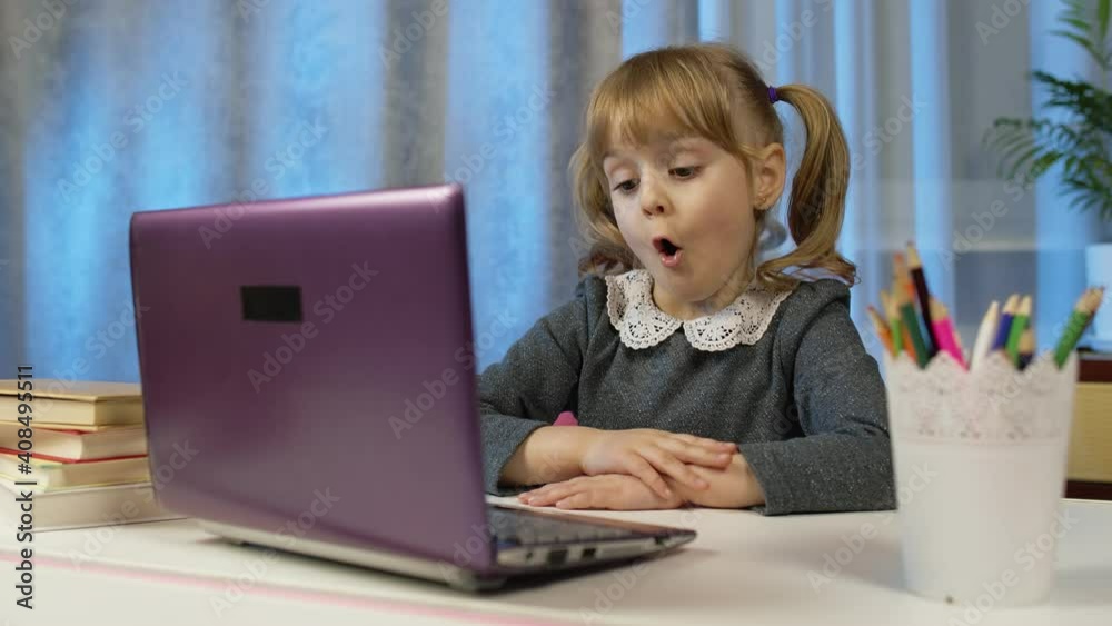 Child schoolgirl learning lessons being at home sitting at table using laptop digital computer. Portrait of kid girl distance education. Studying during coronavirus lockdown. Slow motion. 6k downscale Child schoolgirl learning lessons being at home sitting at table using laptop digital computer. Portrait of kid girl distance education. Studying during coronavirus lockdown. Slow motion. 6k downscale
