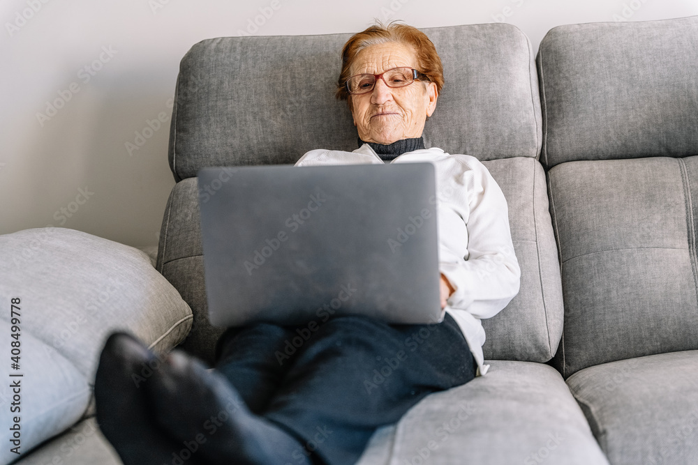 Calm senior woman browsing laptop in living room