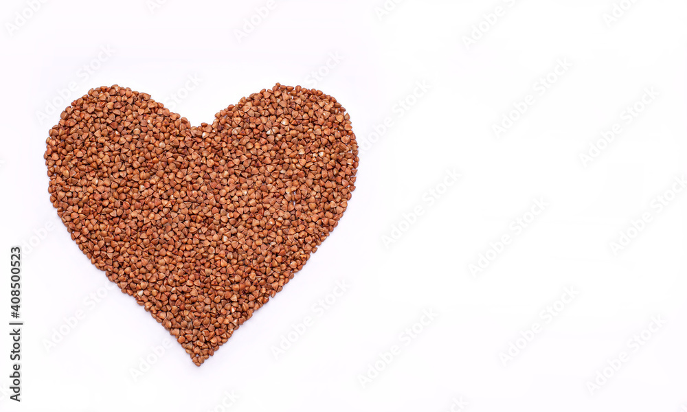 Buckwheat is laid out in the shape of a heart on a white background. Buckwheat is laid out in the shape of a heart on a white background.