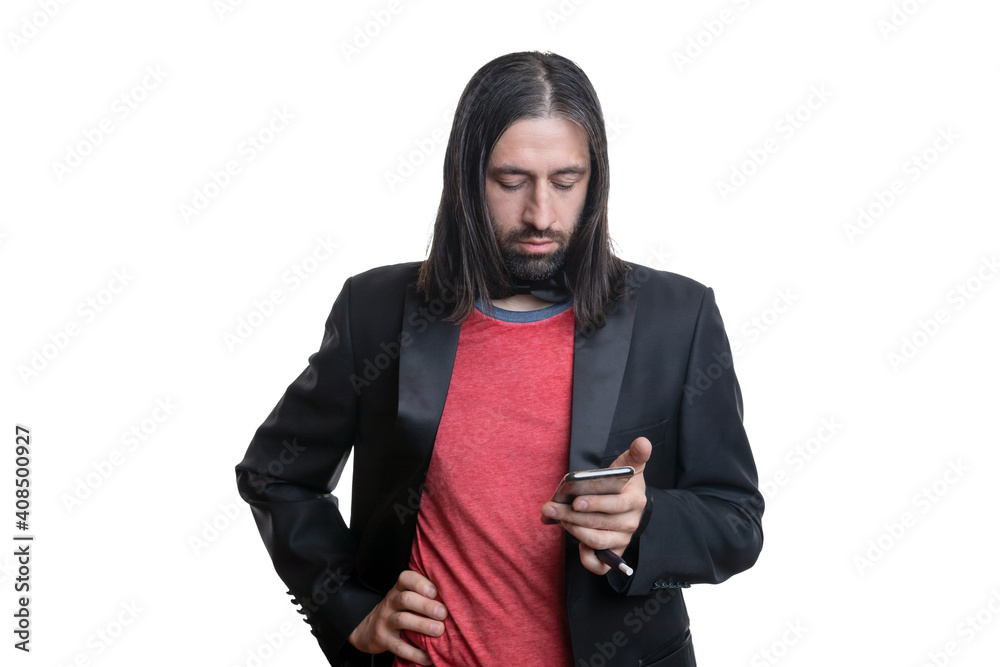 A man with long hair and a beard with an electronic cigarette with sticks and a phone in his hands on a white background. He is wearing a black jacket and a red T-shirt and a bow tie around his neck.