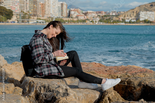 Pretty girl outdoors, she writes in her notebook, stories and thoughts for her book that she will publish. lifestyle concept