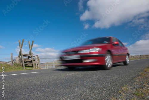 Red car speeding on mountain road in Devon