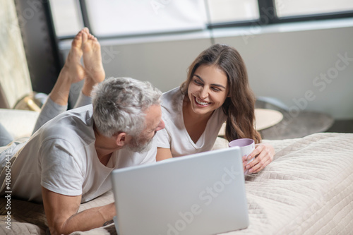Woman and man communicating lying in front of laptop