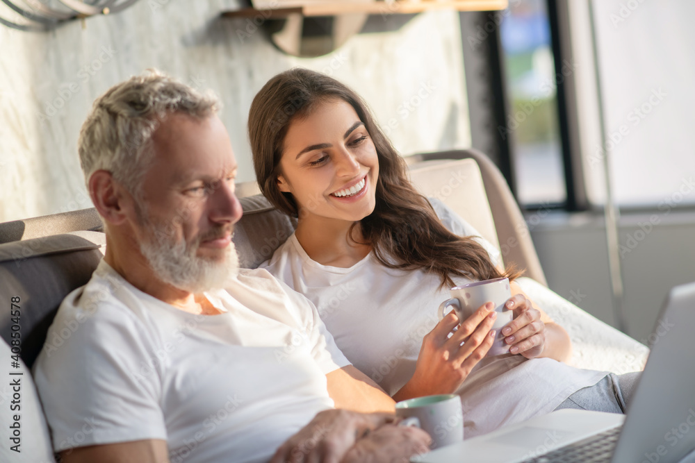 Involved man and woman with coffee looking laptop