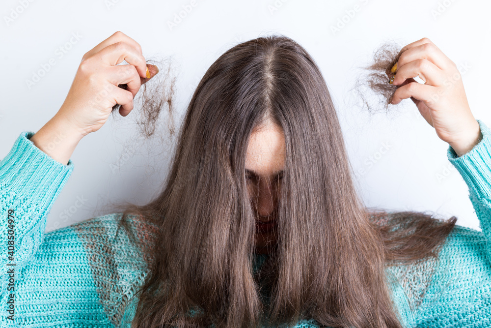 Fototapeta premium Woman holding bundles of hair. lost hair in hands.