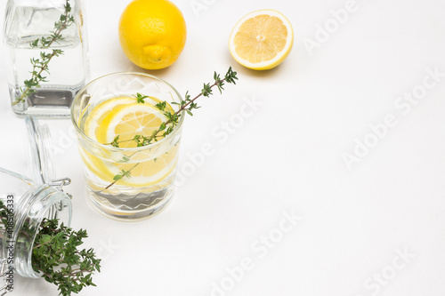 Lemon drink in glass. Thyme sprigs in glass. Lemons on table