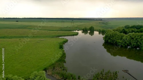 Aerial cinematic: drone flies above a beautiful summer landscape with a river while sunset. Aerial view from drone flies over a amazing landscape in spring. Bird view to the long river