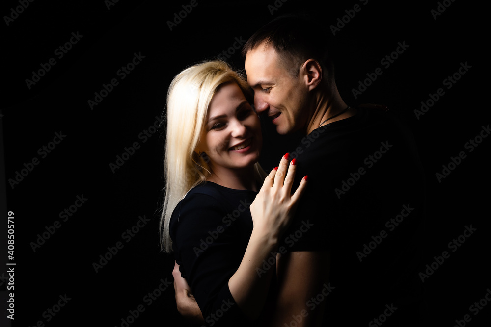 Young couple in love hug each other on the black background