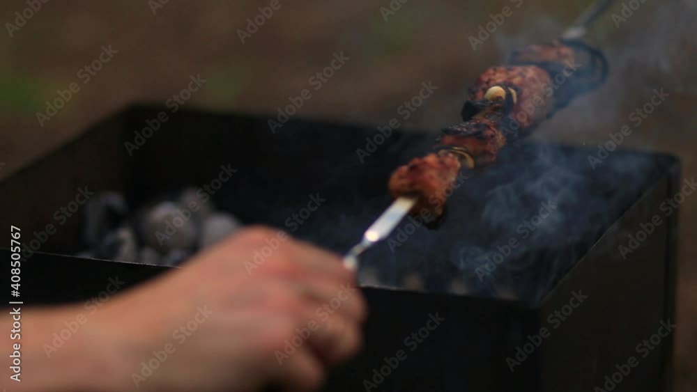 Pork meat on skewers is cooked on grill with burning coals outdoors in forest Pork meat on skewers is cooked on grill with burning coals outdoors in forest