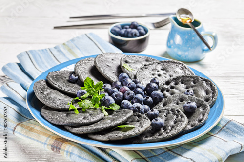 black sweet pancakes served with berries and mint