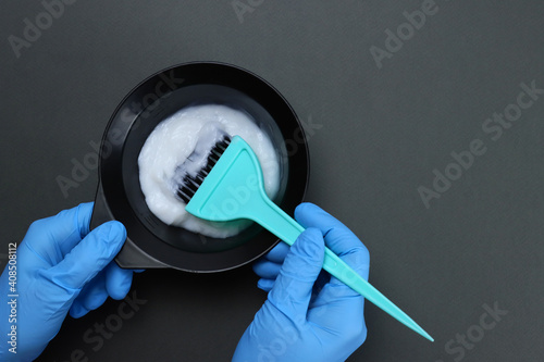 barber mixes the hair dye with a brush in a bowl photo