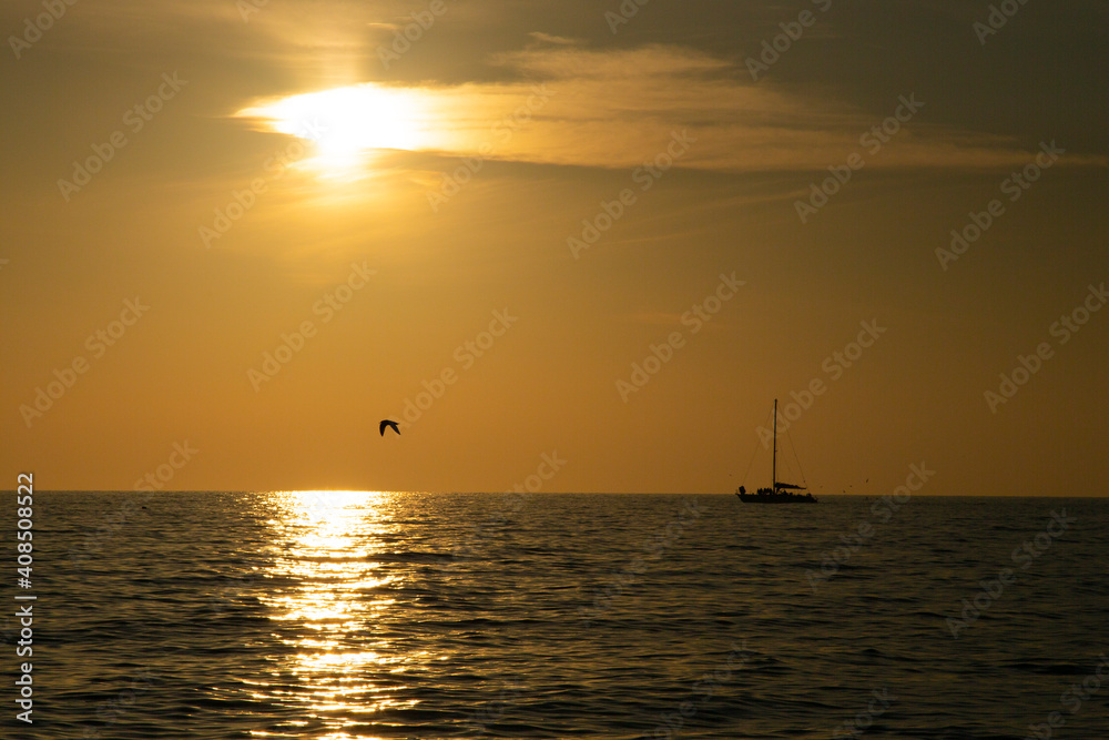 Fishing boat on the horizon, sunset on the sea. Calm sea, coral sky, evening fishing Fishing boat on the horizon, sunset on the sea. Calm sea, coral sky, evening fishing