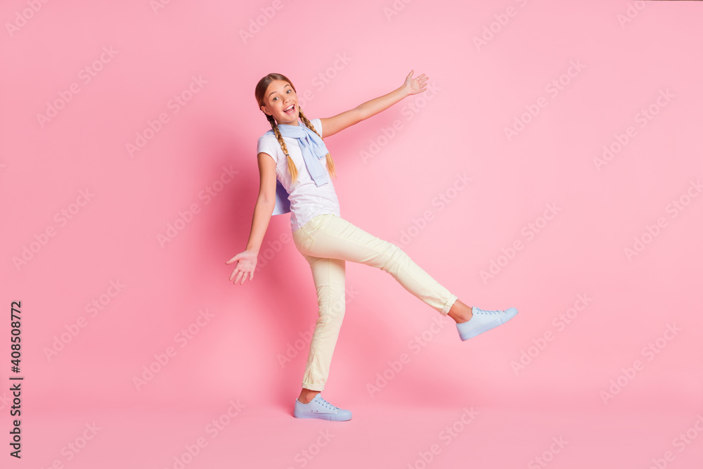Full size profile photo of optimistic girl wear white t-shirt sweater trousers sneakers isolated on pink color background
