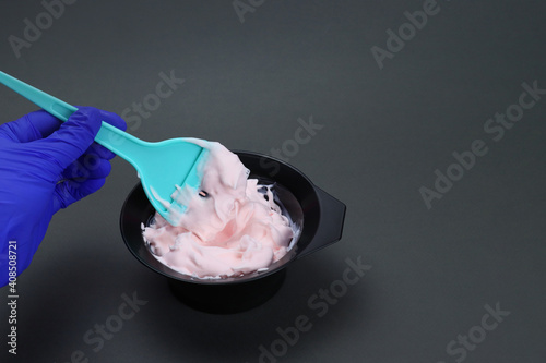 barber mixes the hair dye with a brush in a bowl photo