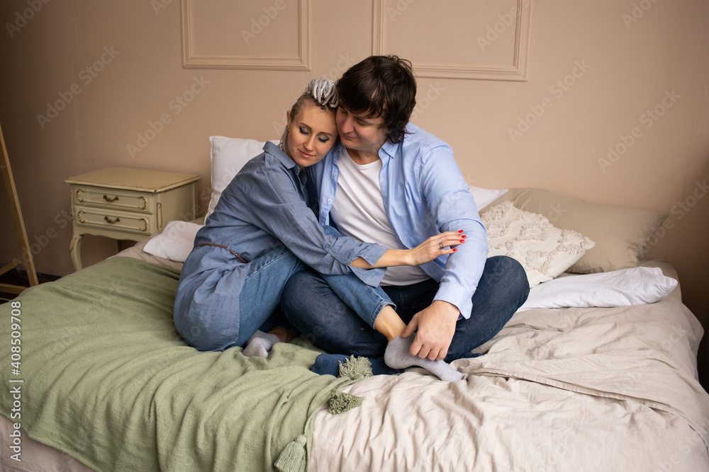 Celebrating Saint Valentine's Day. Beautiful young couple in bedroom sitting on bed and hugging. Celebrating Saint Valentine's Day. Beautiful young couple in bedroom sitting on bed and hugging.