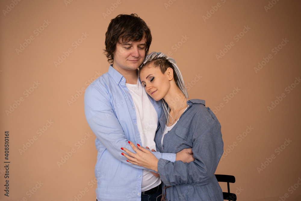 Happy couple in love are hugging and smiling isolated on beige background. Celebrating Saint Valentine's Day Happy couple in love are hugging and smiling isolated on beige background. Celebrating Saint Valentine's Day