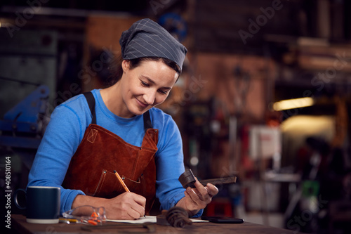 Female Blacksmith Wearing Headscarf Working On Design In Forge