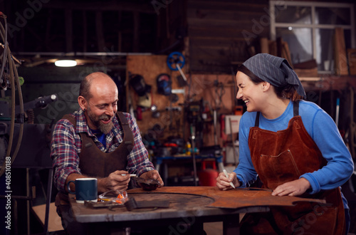 Male And Female Blacksmith Working On Design In Forge Together