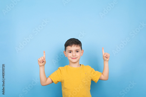 Cheerful little boy looking and pointing up with both hands