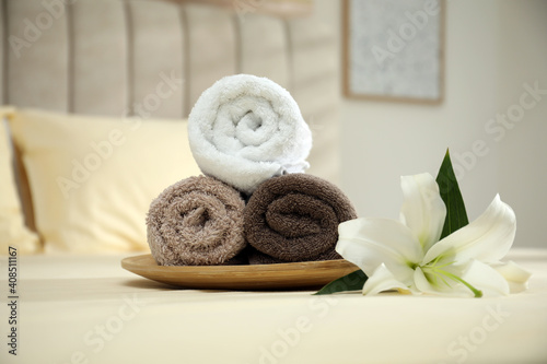 Rolled clean towels and flower on bed indoors