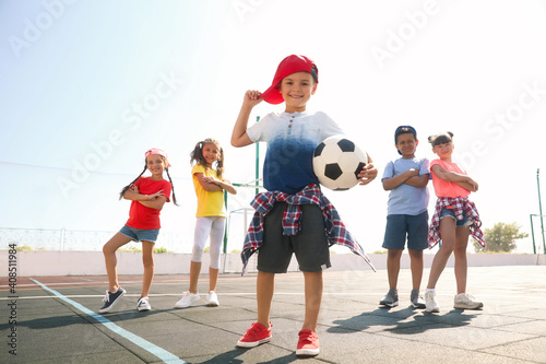 Cute children with soccer ball at sports court on sunny day. Summer camp