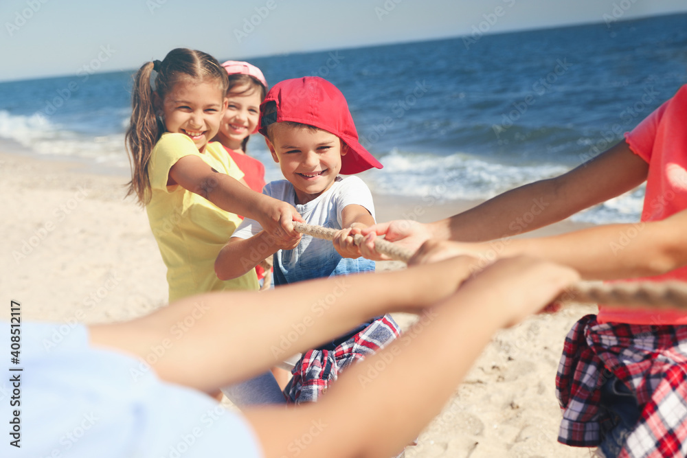 Cute children pulling rope during tug of war game on beach. Summer camp Cute children pulling rope during tug of war game on beach. Summer camp