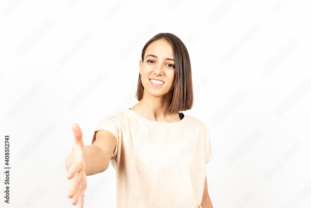 A pretty latin woman offering a handshake while looking to the camera.