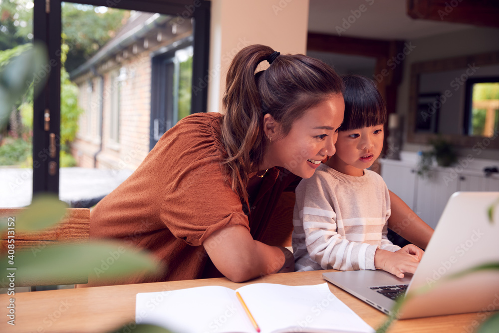 Asian Mother Helping Home Schooling Son Working At Table In Kitchen On Laptop Asian Mother Helping Home Schooling Son Working At Table In Kitchen On Laptop