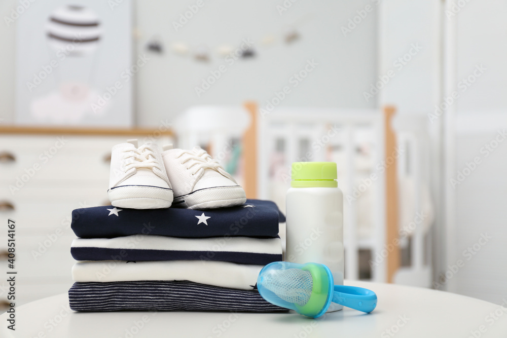 Stack of baby clothes, shoes and accessories on white table indoors Stack of baby clothes, shoes and accessories on white table indoors
