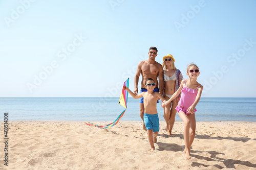 Happy family with kite at beach on sunny day