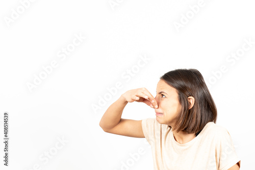 Bad smell concept. Side view of a young latin woman pinching her nose with nasty face. photo