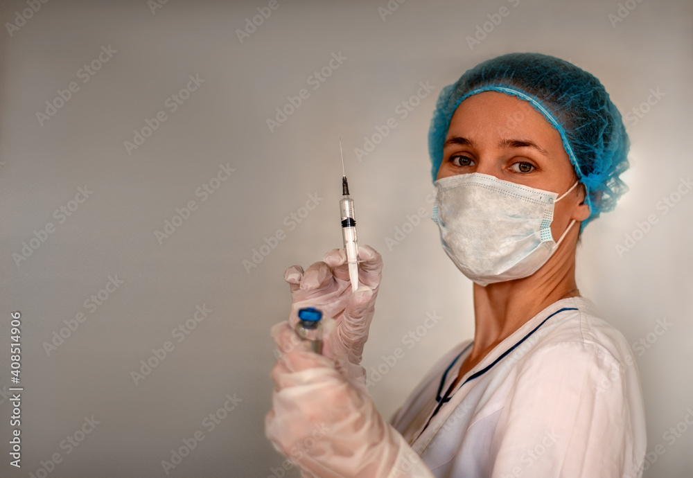 Nurse with a syringe and a vaccine in her hands on a light background. Girl in mask and medical uniform. Medical staff. Vaccination. Vaccination covid-19. Copy space. Nurse with a syringe and a vaccine in her hands on a light background. Girl in mask and medical uniform. Medical staff. Vaccination. Vaccination covid-19. Copy space.